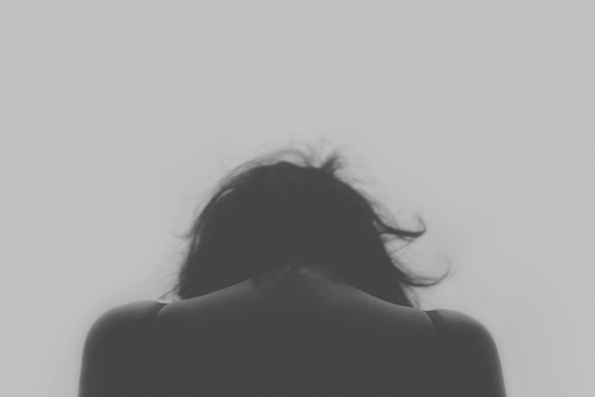 A person sitting with their head down, stressed